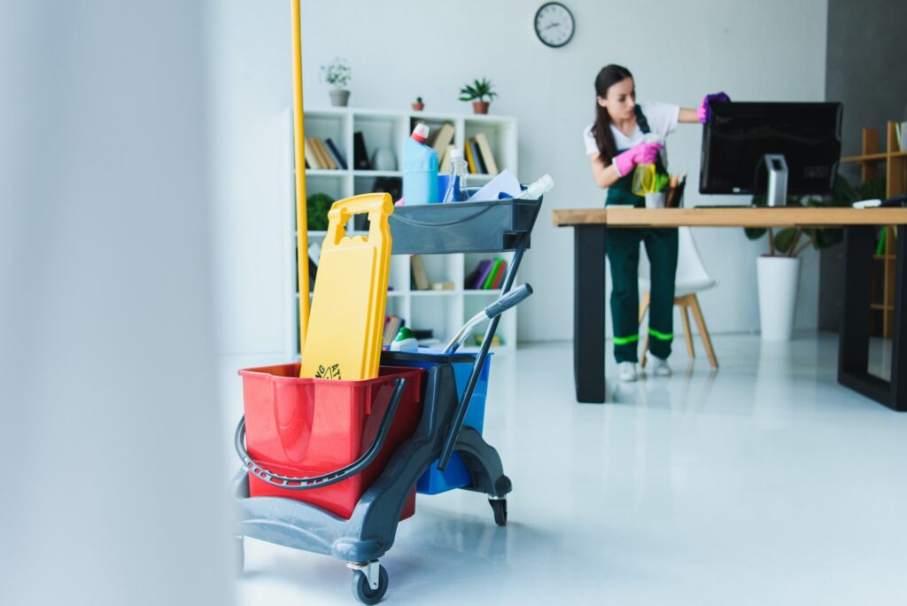 A woman in an office setting with cleaning supplies.