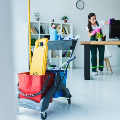 A woman in an office setting with cleaning supplies.